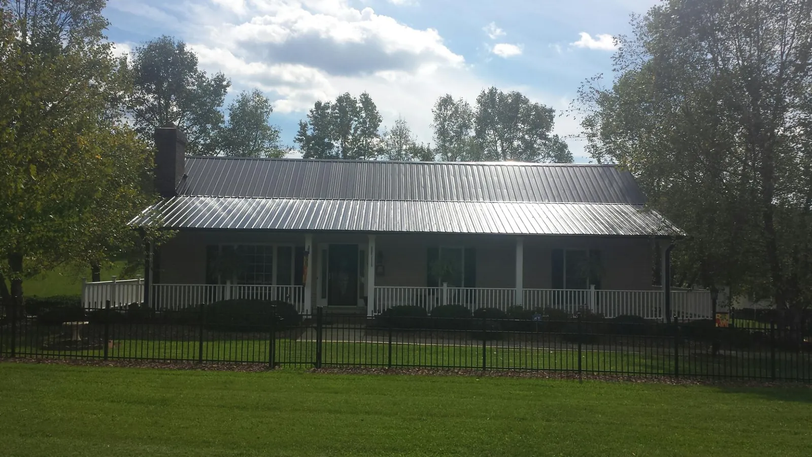 Gray metal roof on a brick ranch with a full width front porch — Gutter Guard Installation work by our crew in Rhodhiss