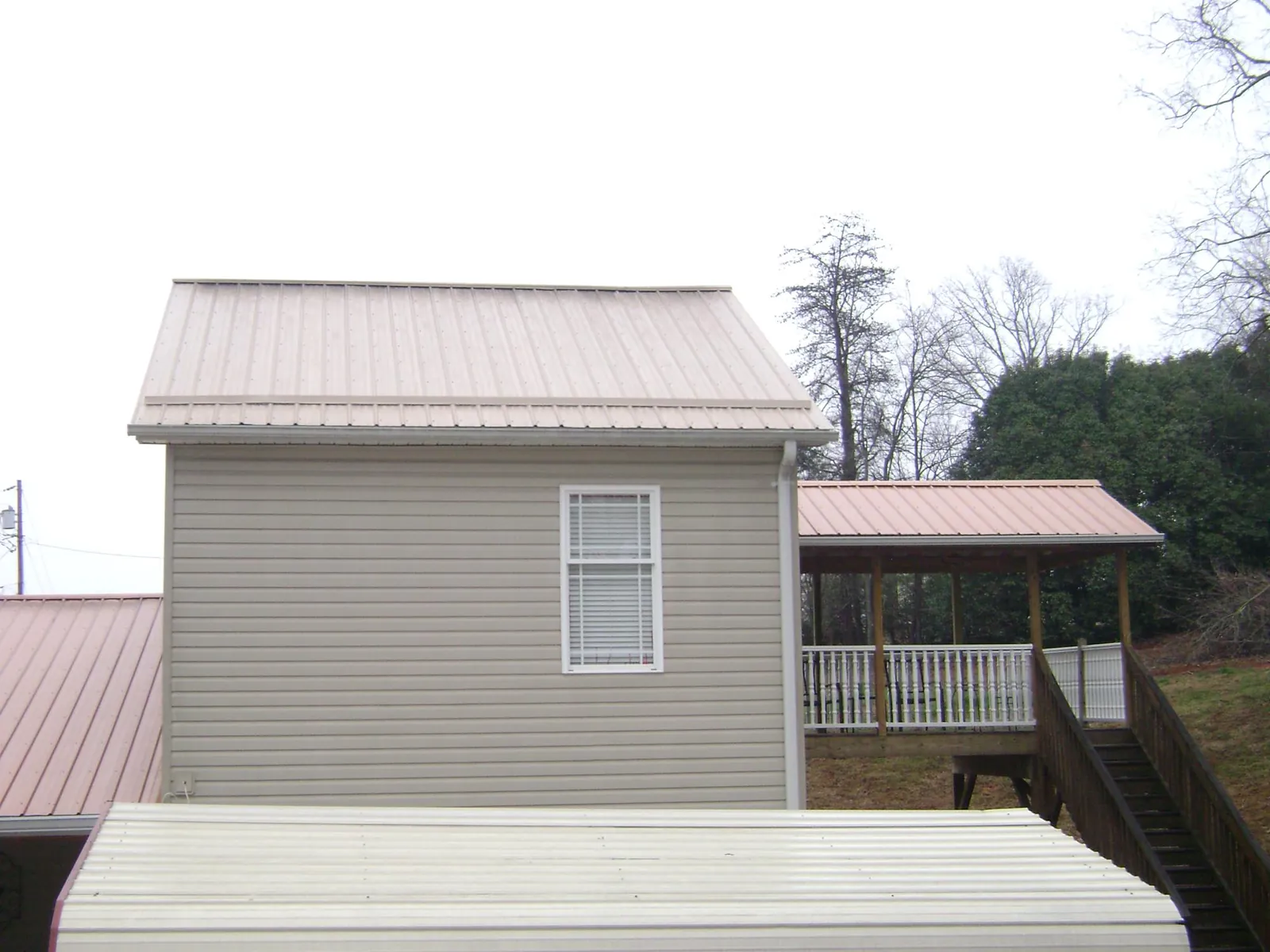 Tan metal roofs on a two story addition and attached porch, from a Roof Replacement job in Rhodhiss