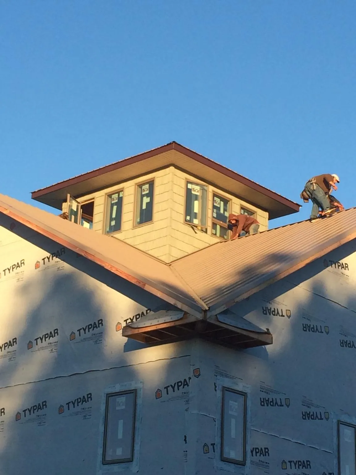 Roofers working around a rooftop cupola on a new metal roof at sunset — Roof Waterproofing in Rhodhiss by Roofing Brothers